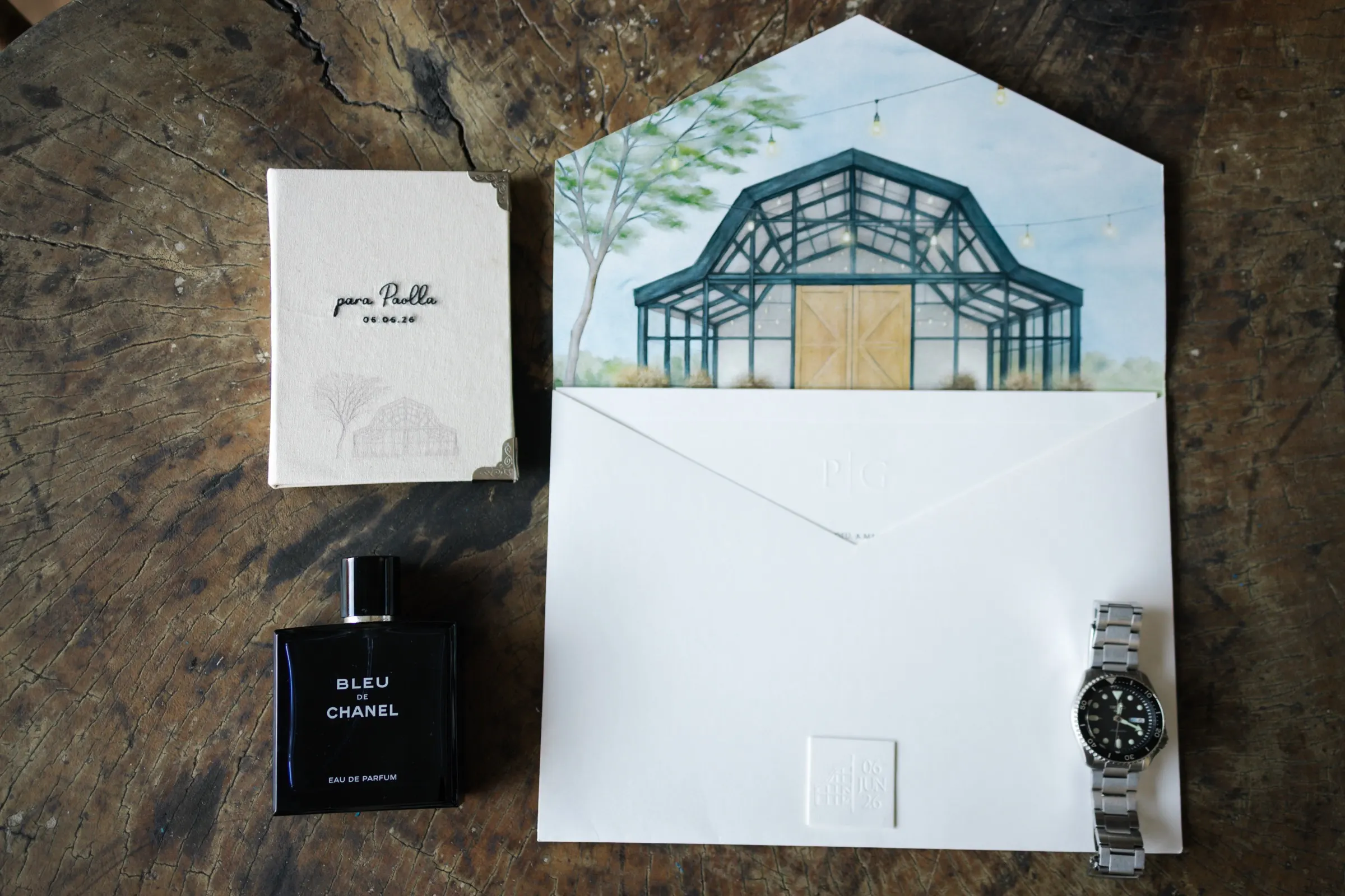 Convite com a ilustração do celeiro, perfume e relógio do noivo
